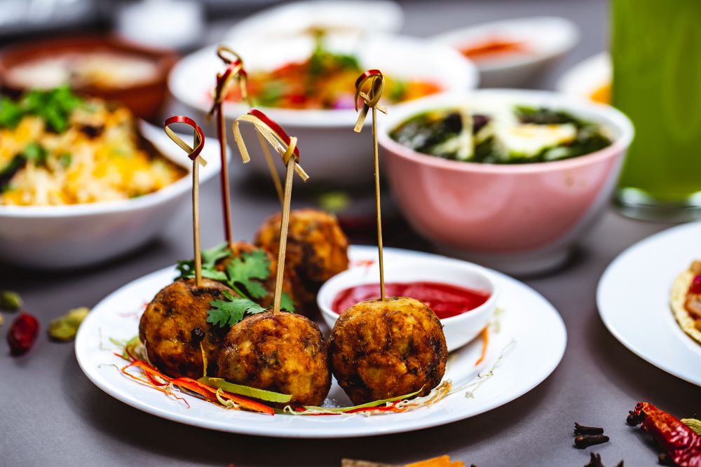 4 Lamb meatballs on a stick with a tomato purre on the side 